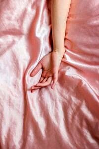 kobieca ręka na różowym prześcieradle