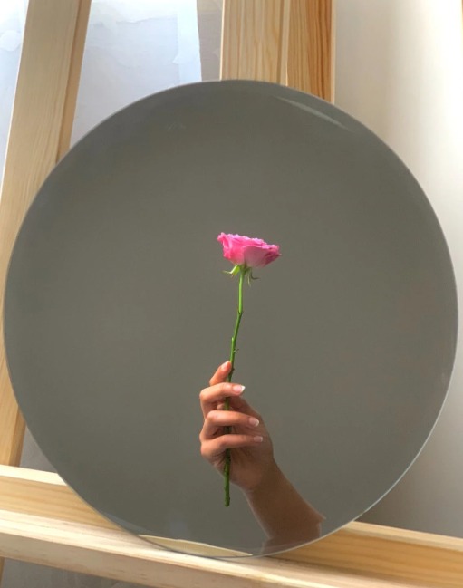 Różowy kwiatek trzymany przez kobietę na tle szarego talerza