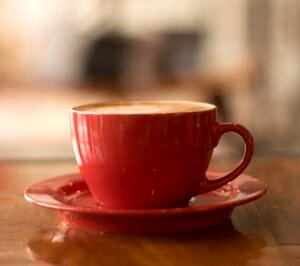czerwona filiżanka na czerwonym talerzyku pełna kawy